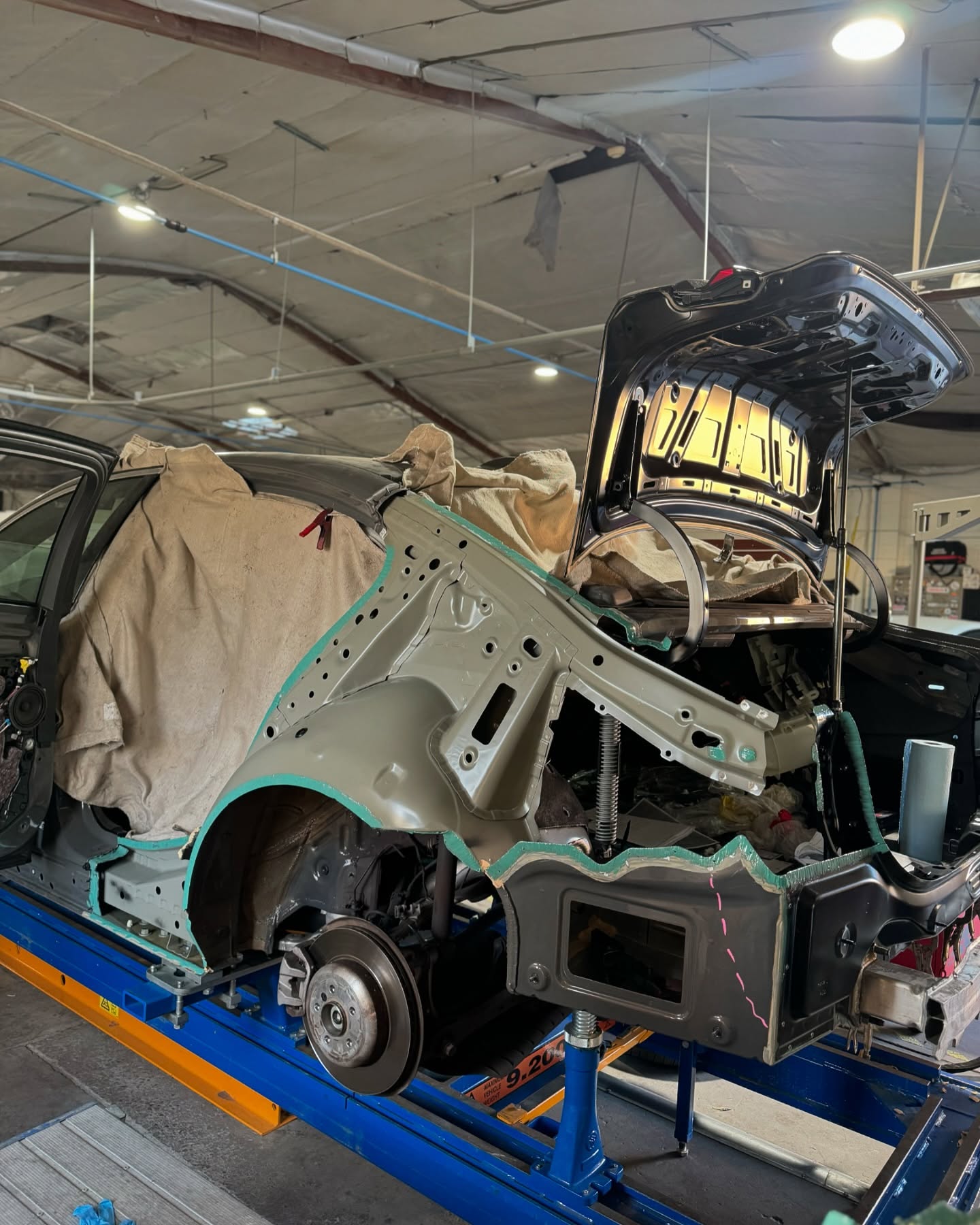 BMW 540i quarter panel replacement using OEM adhesive at Fullerton collision repair shop Supreme Collision Center